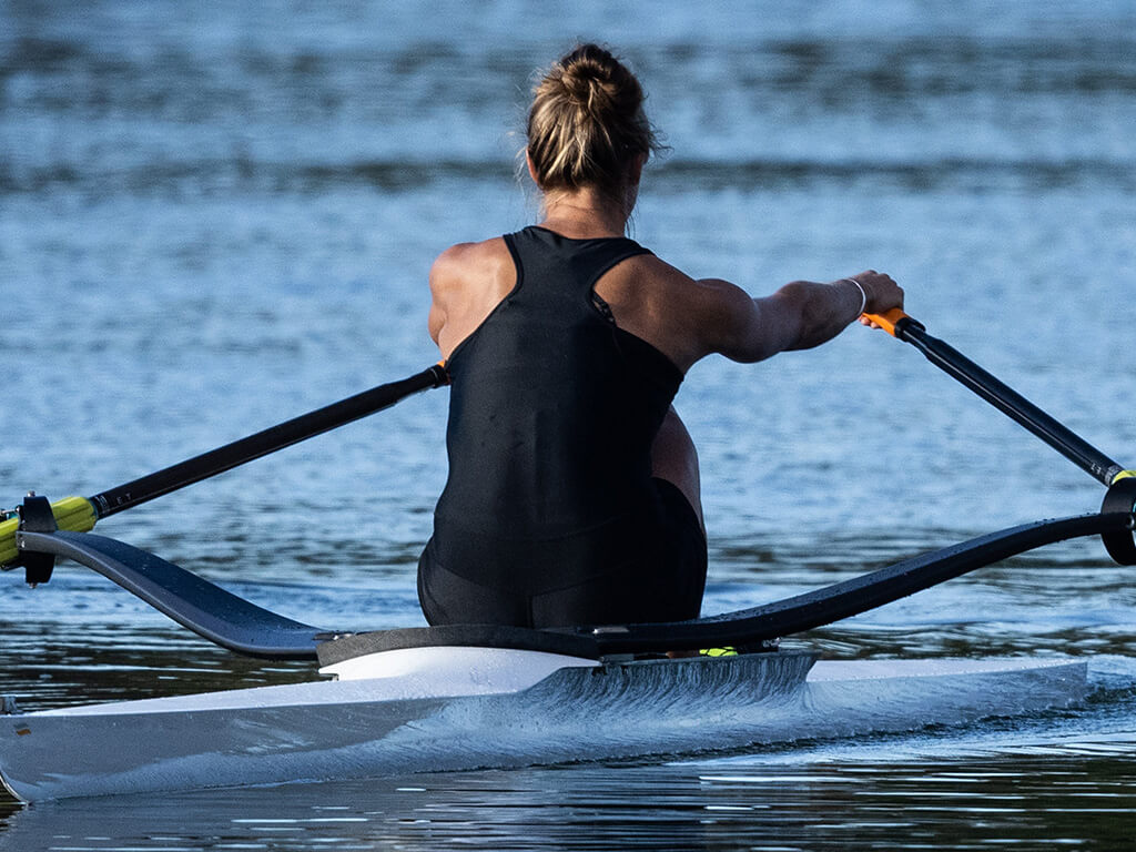 Close up of a rowers back in a single scull rowing boat on the water