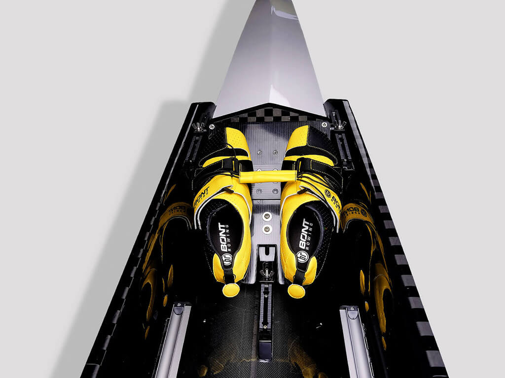 Internal view of an SL Racing single skiff boat with black and yellow shoes in front.