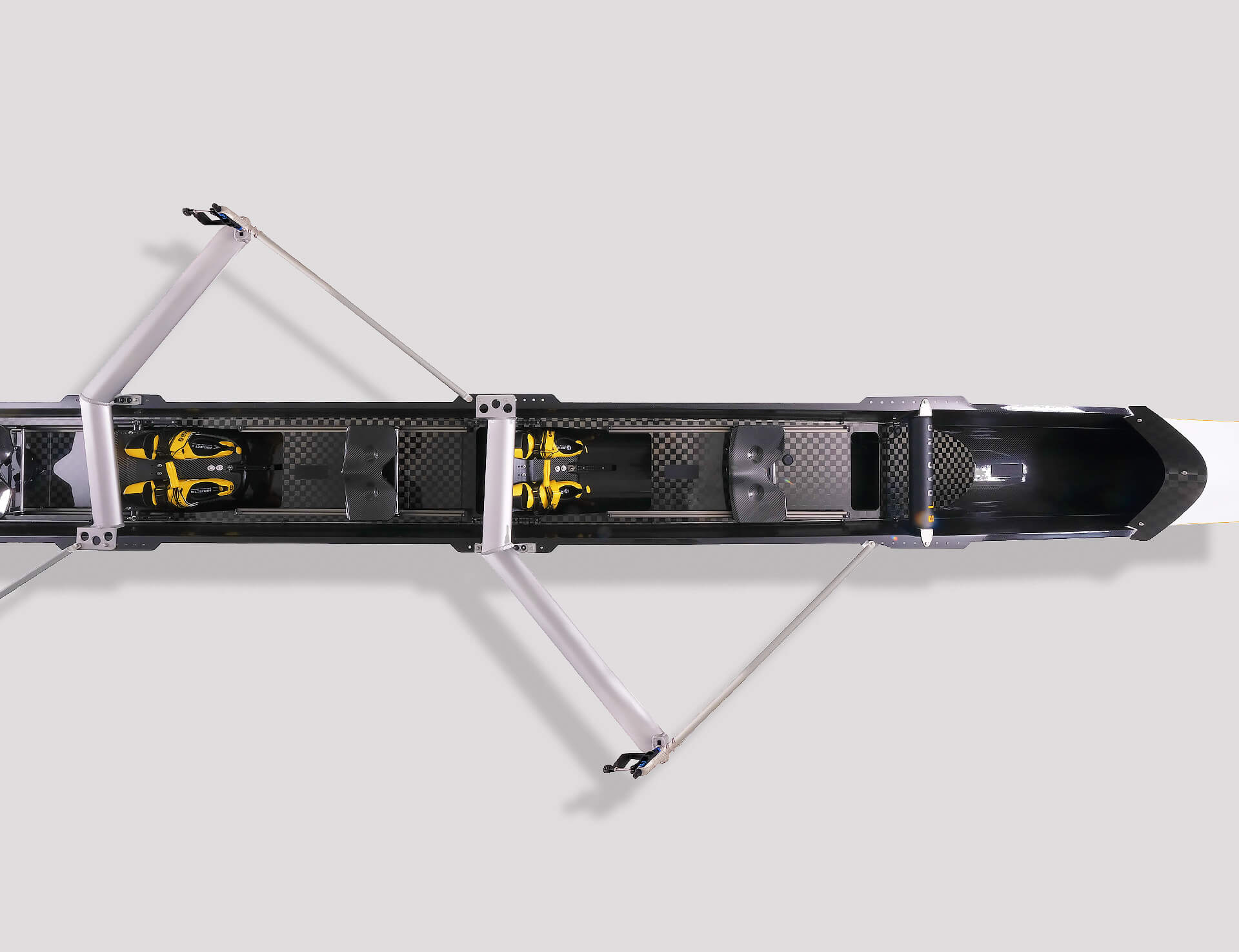 Overhead view of a double scull rowing boat on grey background with aluminium rigging, black and yellow boat shoes and checkered carbon internal detail
